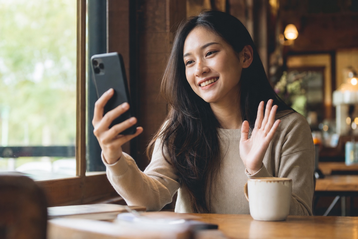 A young Indonesian woman doing a video call on her phone before meeting a match in person