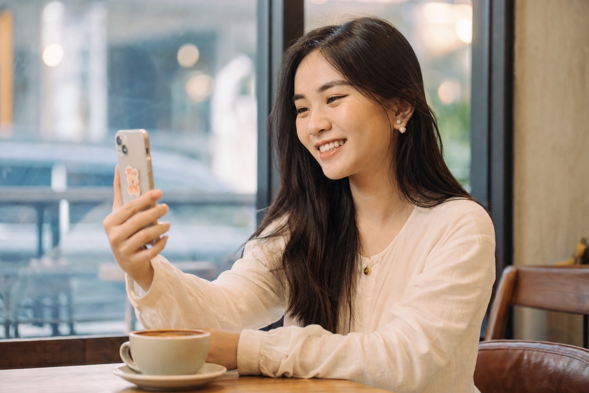 A young Vietnamese woman doing a video call on her phone before meeting a match in person