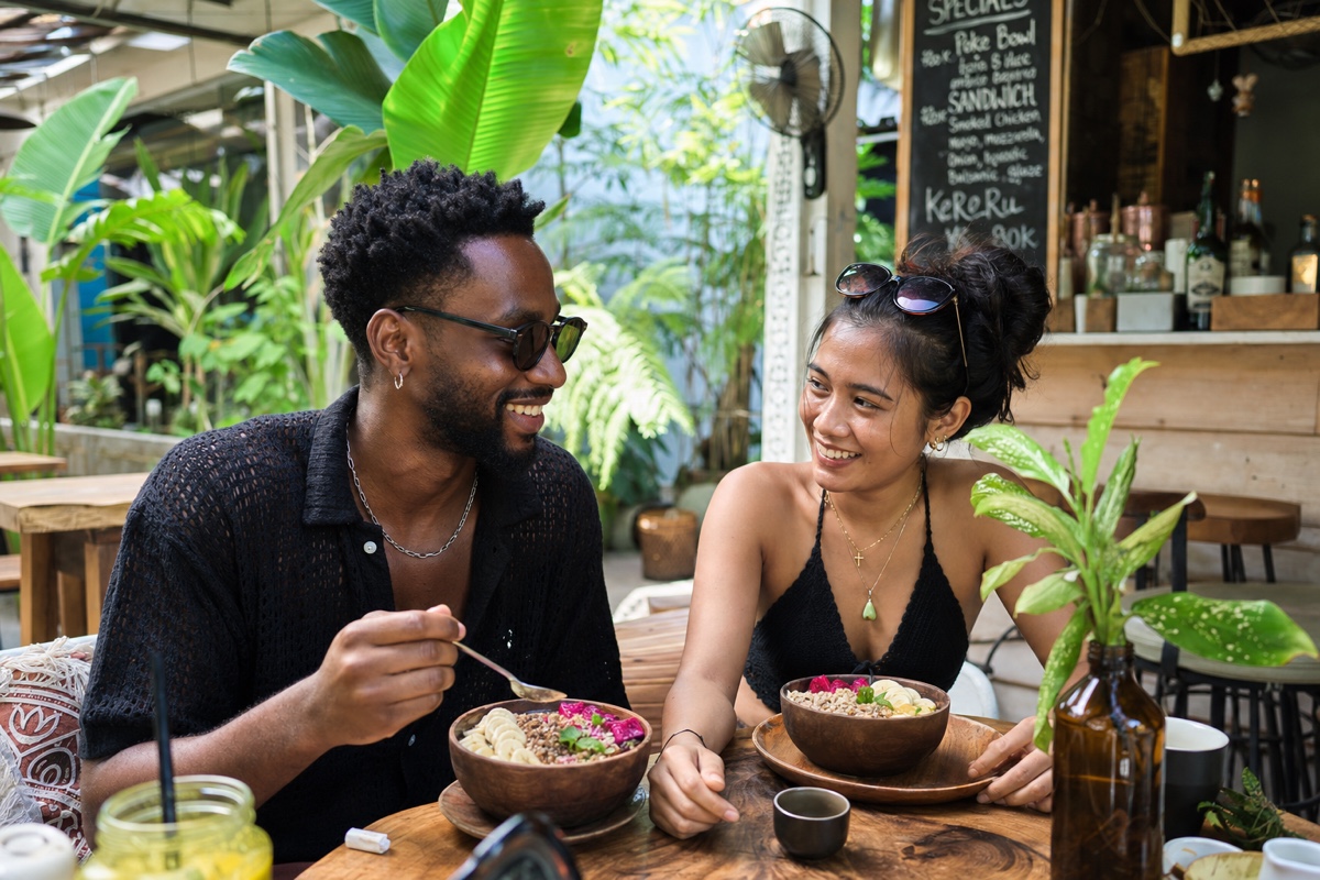 A foreign man and a Balinese woman on a relaxed brunch date at a leafy Canggu cafe