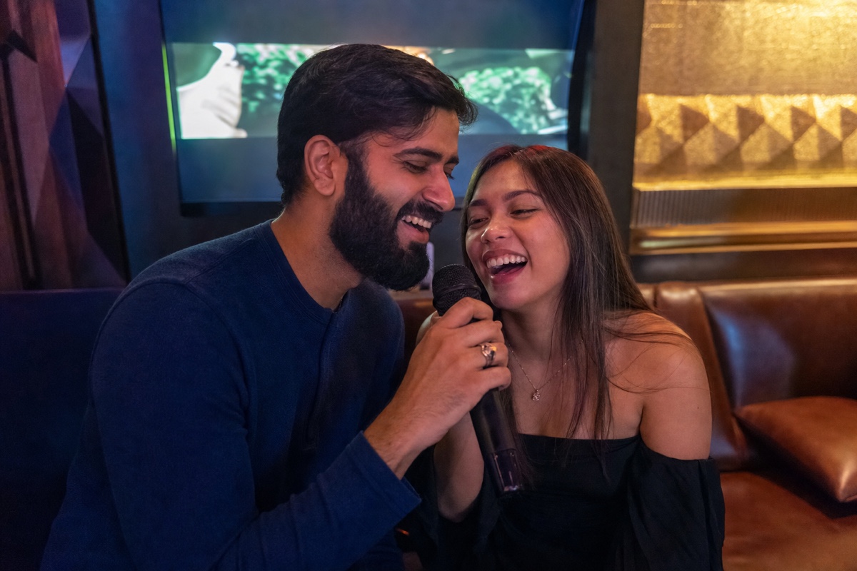 A foreign man and a Filipina sharing a microphone for a duet at a karaoke bar