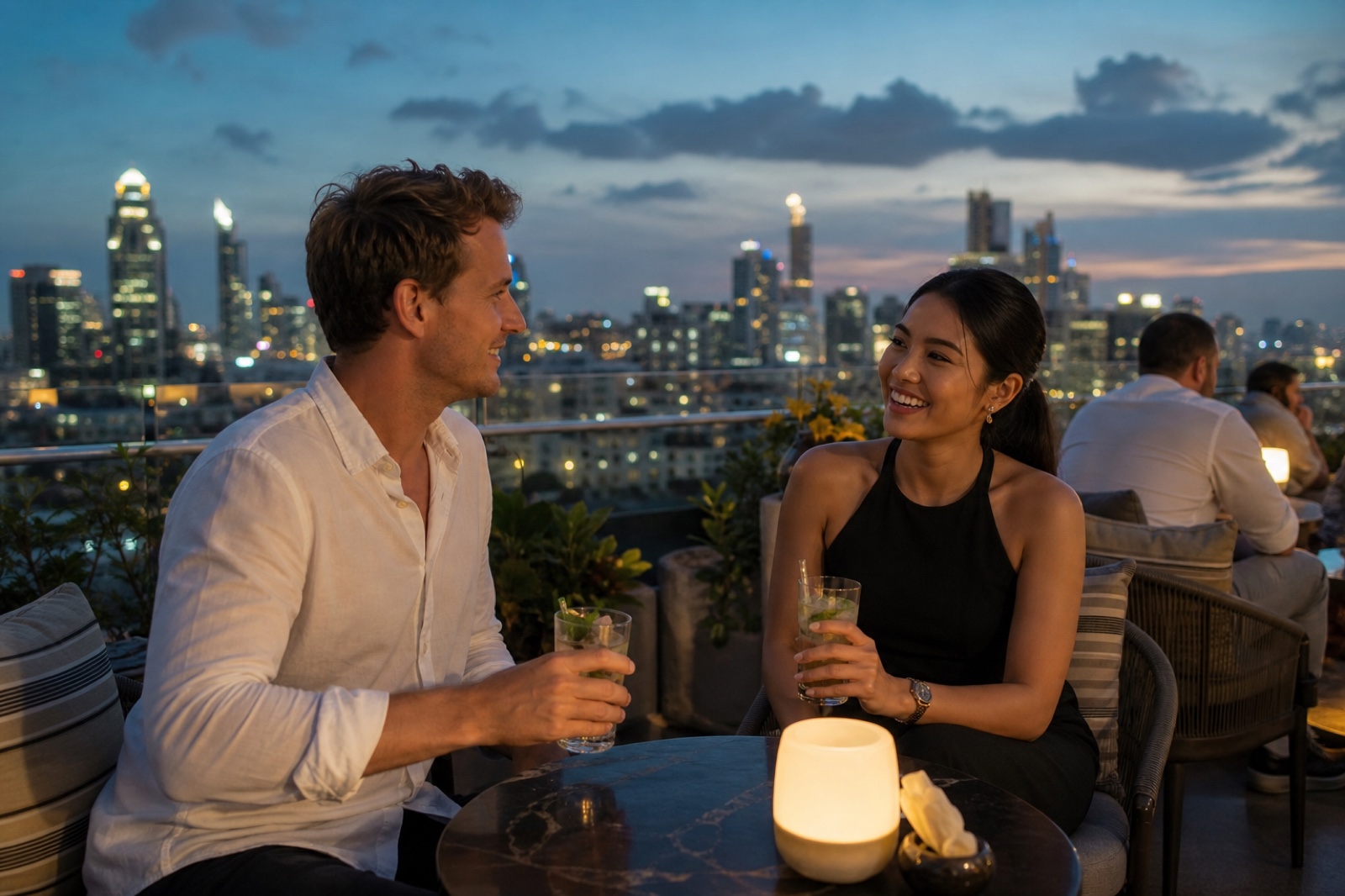 A foreign man and a Thai woman meeting and chatting over drinks at a relaxed Bangkok rooftop bar in the evening